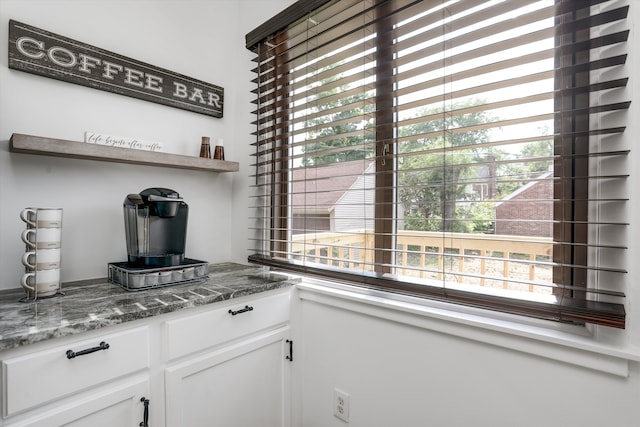 bar with white cabinetry and dark stone counters