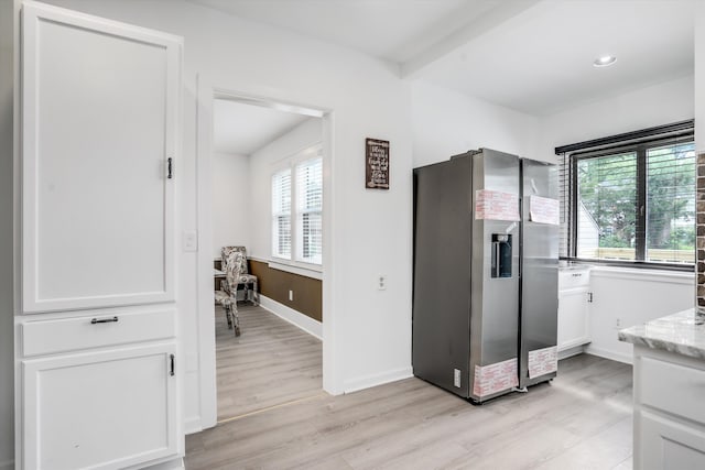 interior space with light stone countertops, stainless steel fridge with ice dispenser, light hardwood / wood-style floors, and white cabinetry