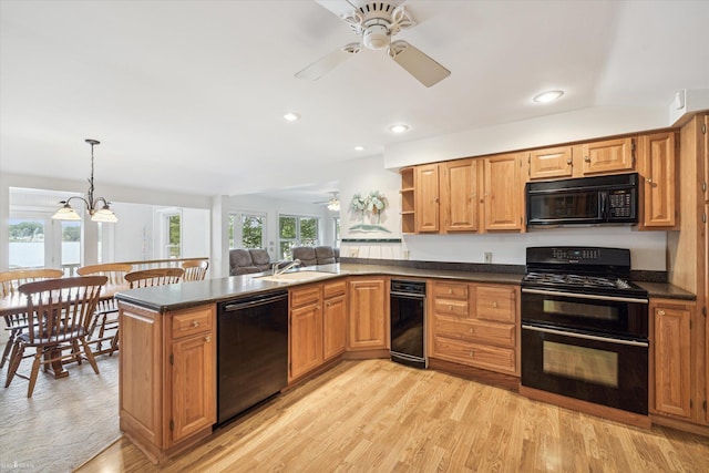 kitchen featuring decorative light fixtures, black appliances, sink, kitchen peninsula, and plenty of natural light