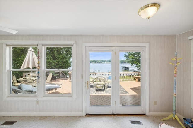 doorway to outside with a water view, carpet flooring, and a wealth of natural light