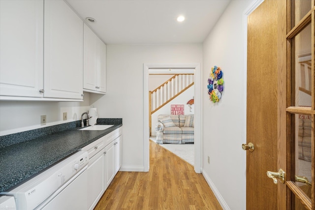 interior space featuring sink, dishwasher, light hardwood / wood-style floors, and white cabinets