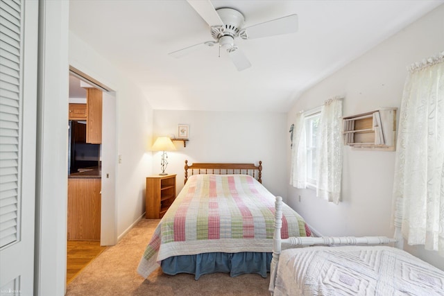 bedroom with black refrigerator, ceiling fan, light colored carpet, and vaulted ceiling