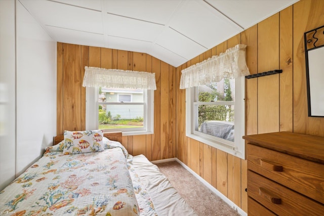 carpeted bedroom with vaulted ceiling and wooden walls