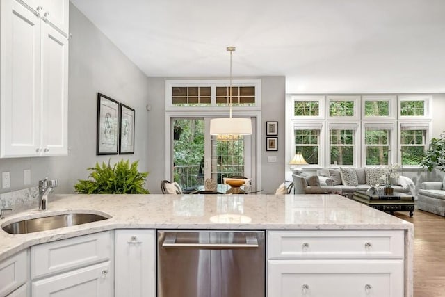 kitchen featuring white cabinets, sink, stainless steel dishwasher, light wood-type flooring, and light stone counters