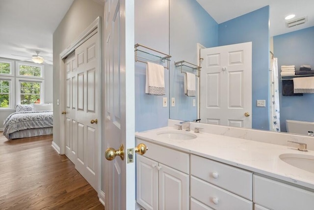 bathroom with hardwood / wood-style floors, vanity, toilet, and ceiling fan