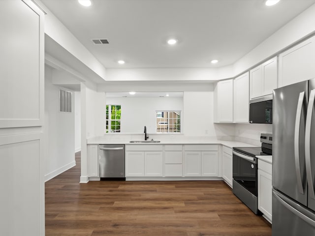 kitchen with dark wood-type flooring, appliances with stainless steel finishes, white cabinets, and sink