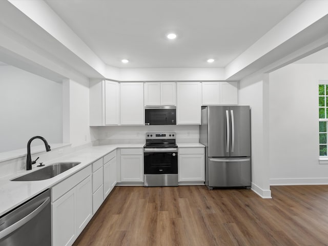 kitchen featuring kitchen peninsula, sink, stainless steel appliances, white cabinets, and dark hardwood / wood-style flooring