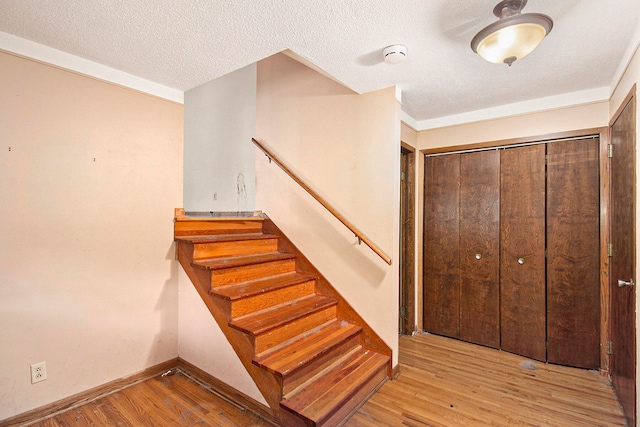 stairway with hardwood / wood-style floors and a textured ceiling