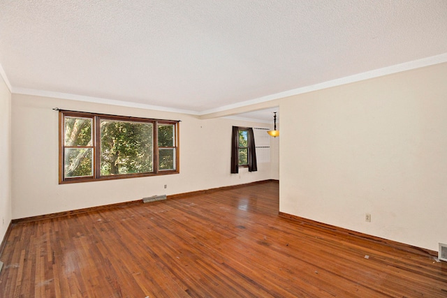 spare room featuring dark hardwood / wood-style flooring, a textured ceiling, and ornamental molding