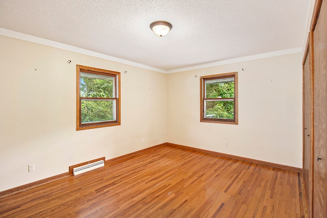 empty room with a textured ceiling, hardwood / wood-style flooring, and ornamental molding