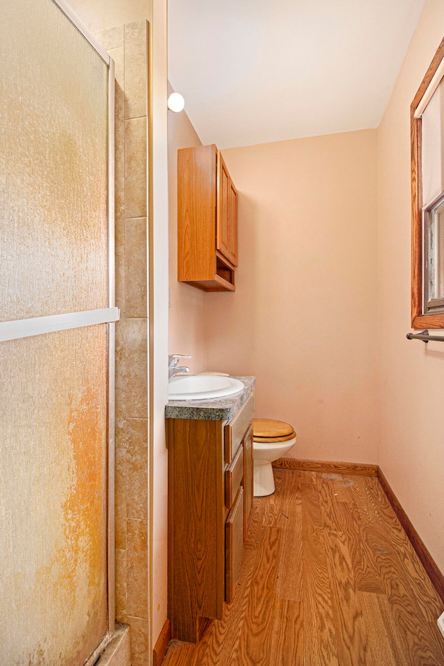 bathroom with walk in shower, toilet, vanity, and hardwood / wood-style flooring