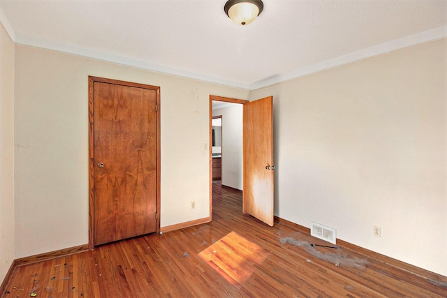 unfurnished bedroom featuring dark wood-type flooring and ornamental molding