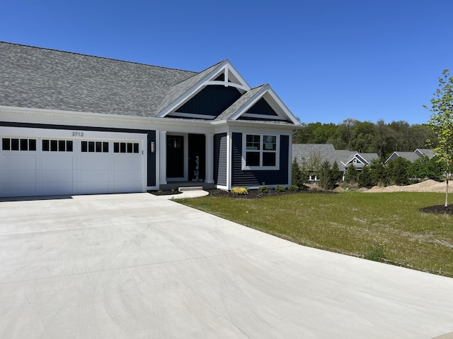 view of front of home featuring a garage, driveway, a front lawn, and a shingled roof