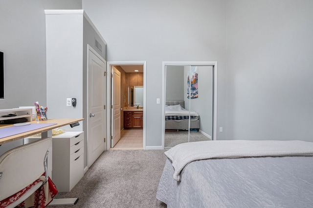 carpeted bedroom with ensuite bathroom, a closet, and sink