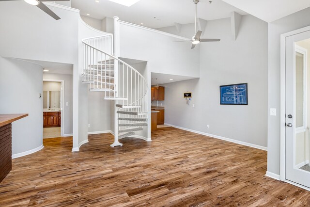 unfurnished living room featuring hardwood / wood-style flooring, ceiling fan, and high vaulted ceiling