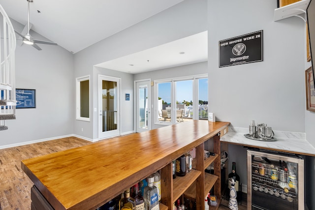 dining space featuring wine cooler, vaulted ceiling, ceiling fan, bar, and wood-type flooring