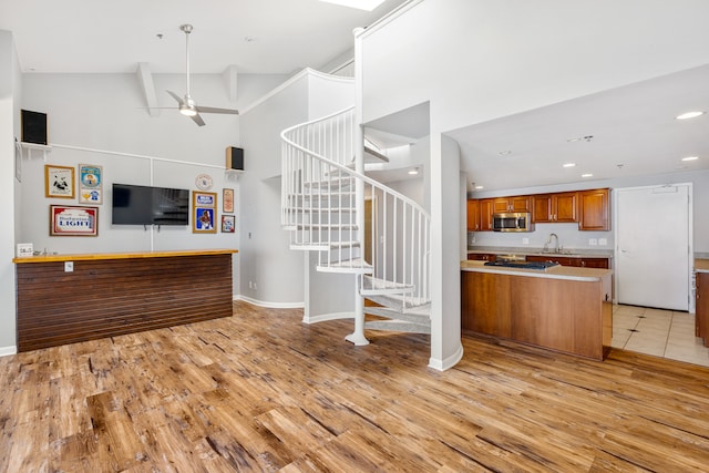 kitchen with high vaulted ceiling, sink, ceiling fan, light wood-type flooring, and stainless steel appliances