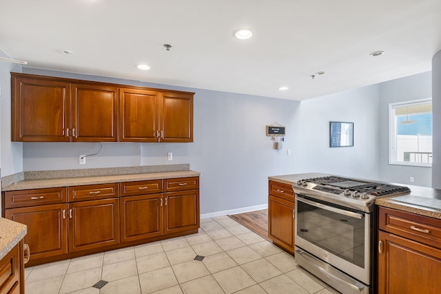 kitchen featuring light stone counters, light tile patterned floors, and stainless steel gas range