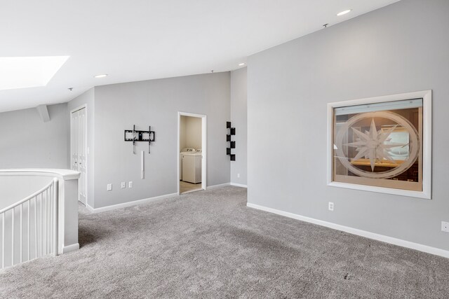 unfurnished room with washer and dryer, lofted ceiling with skylight, and light carpet