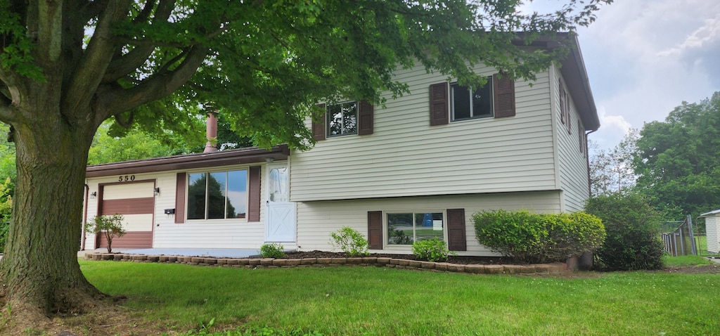 back of property with a lawn and a garage