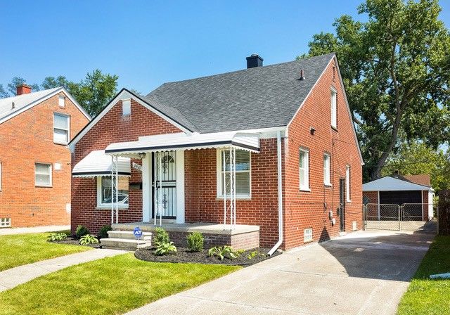 bungalow-style home with a front yard, a garage, and an outdoor structure