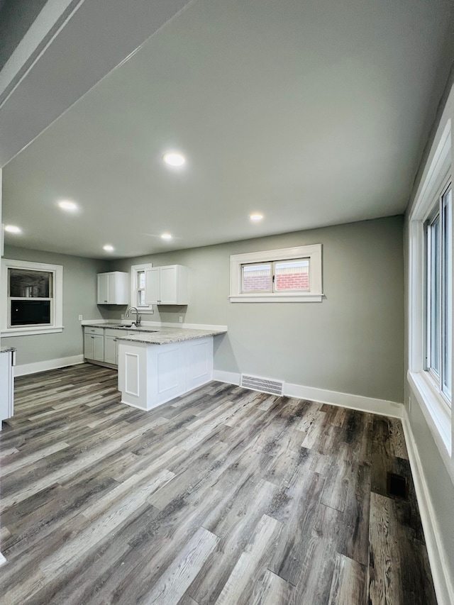 kitchen featuring kitchen peninsula, hardwood / wood-style floors, white cabinets, and a wealth of natural light