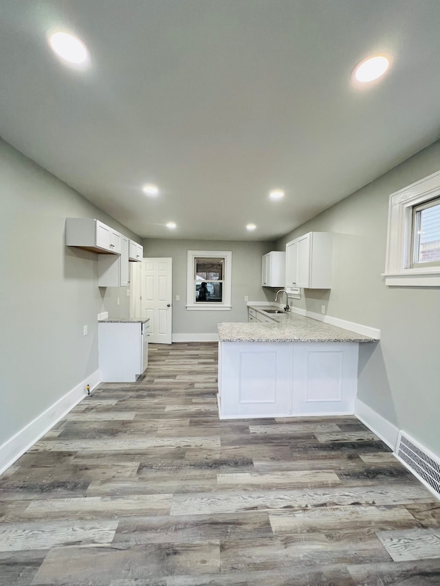 kitchen with kitchen peninsula, white cabinetry, and light hardwood / wood-style floors