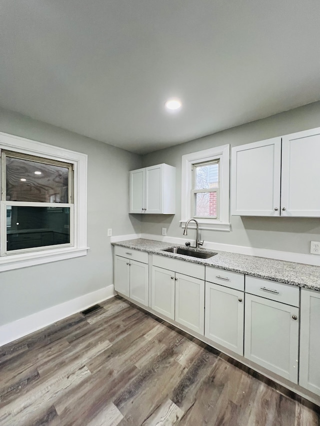 kitchen featuring white cabinets, light stone countertops, dark wood-type flooring, and sink