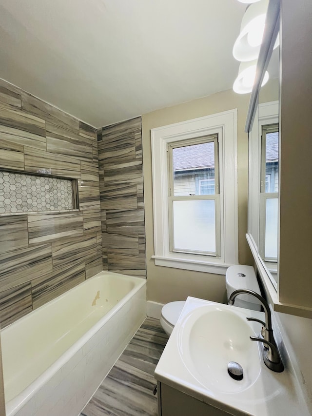 full bathroom featuring hardwood / wood-style floors, vanity, toilet, and tiled shower / bath