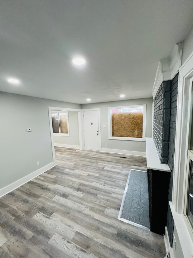 unfurnished room featuring a fireplace, light hardwood / wood-style floors, and a healthy amount of sunlight