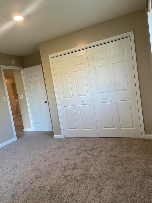 unfurnished bedroom featuring a closet, baseboards, and carpet flooring