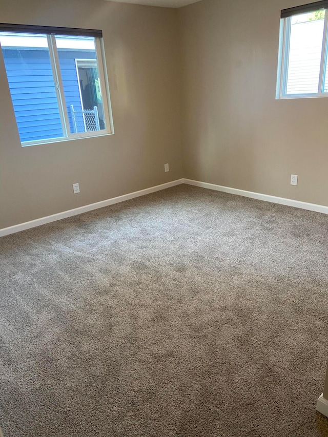 carpeted spare room featuring baseboards