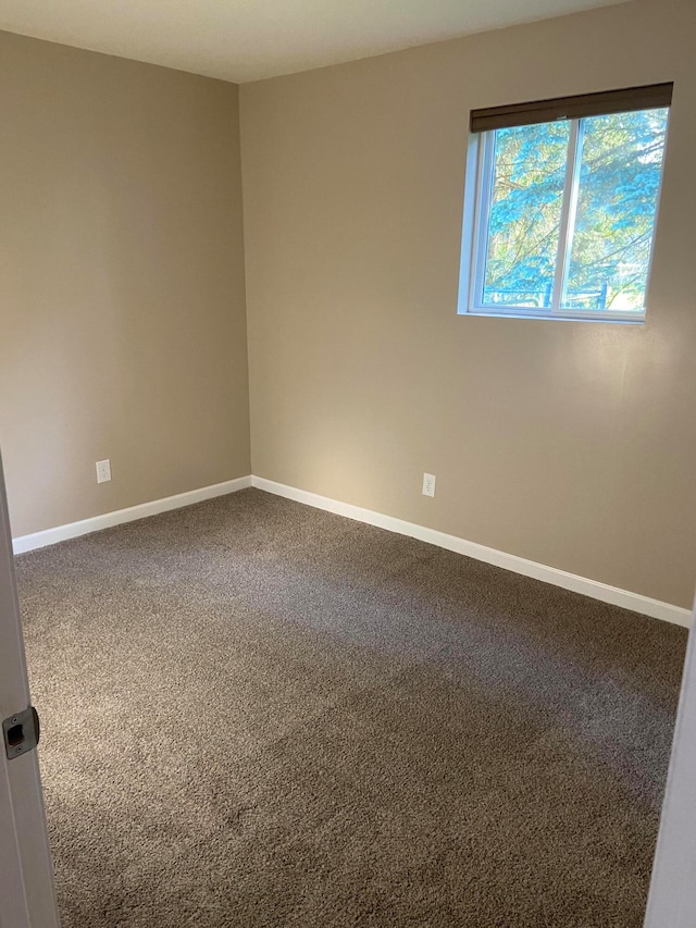 spare room featuring carpet flooring and baseboards