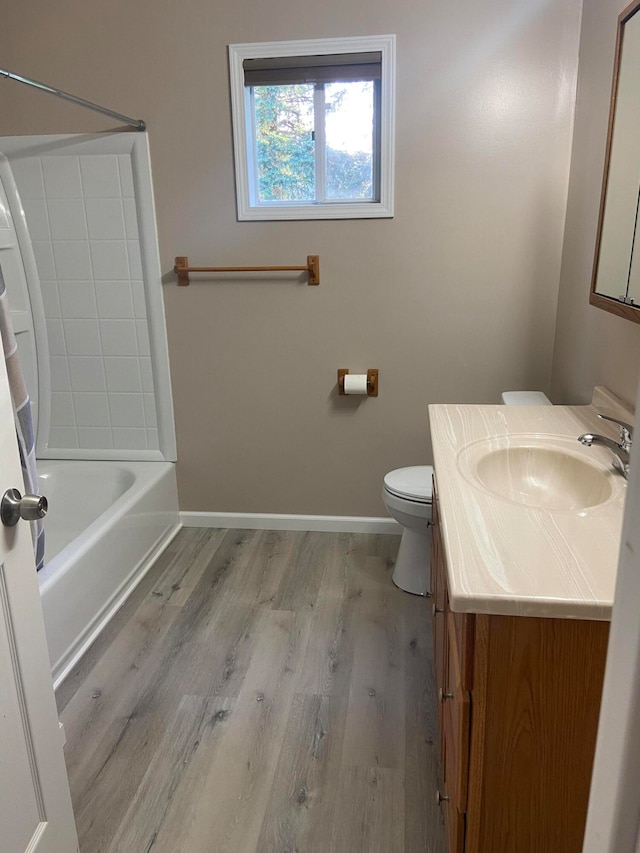 full bath with vanity, wood finished floors, baseboards,  shower combination, and toilet