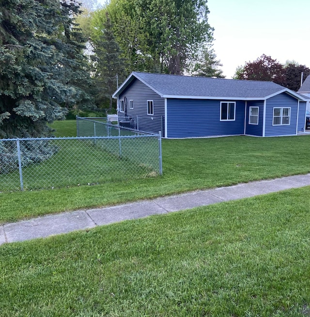 view of home's exterior with a lawn, roof with shingles, and fence