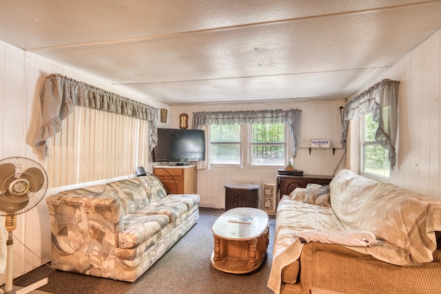 carpeted living room featuring wood walls and a textured ceiling