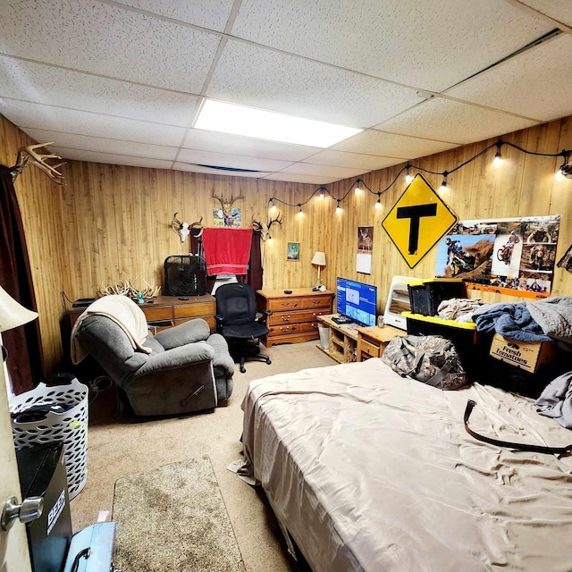 bedroom featuring carpet flooring, a paneled ceiling, and wood walls
