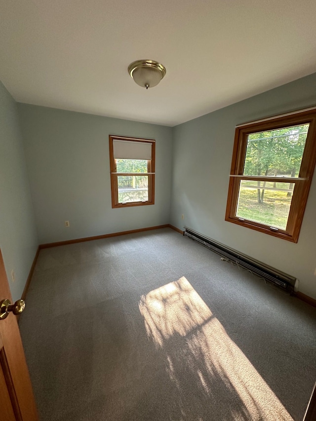 carpeted empty room featuring a baseboard heating unit