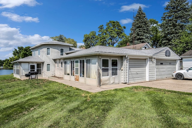 rear view of house with a sunroom, a yard, and a garage