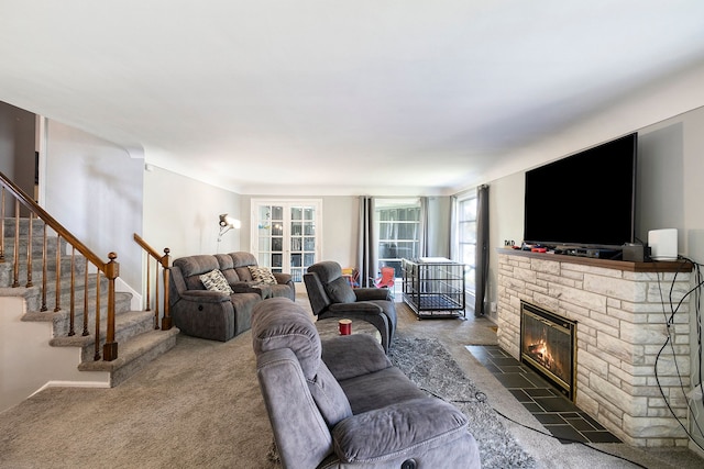 living area with carpet floors, stairs, and a stone fireplace