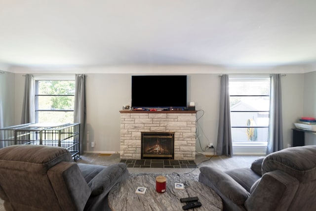 carpeted living room featuring a stone fireplace