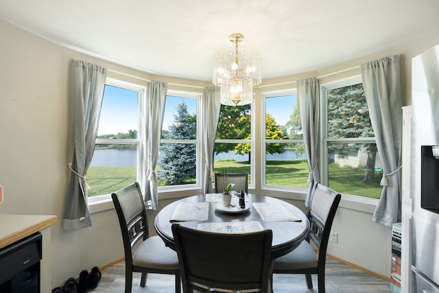 dining space featuring hardwood / wood-style flooring, plenty of natural light, a water view, and an inviting chandelier