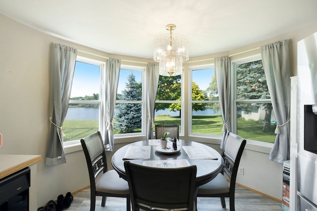 dining area with wine cooler, baseboards, light wood finished floors, an inviting chandelier, and a water view