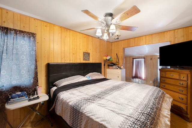 bedroom with ceiling fan and wood walls