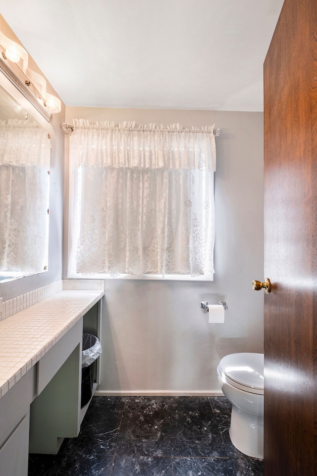 bathroom featuring baseboards, vanity, toilet, and marble finish floor