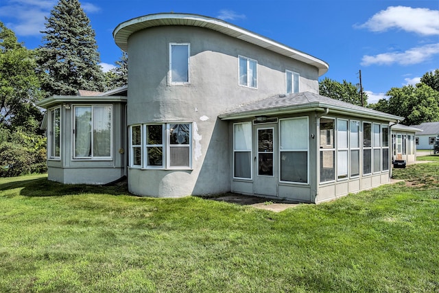 back of property featuring a sunroom, stucco siding, and a yard