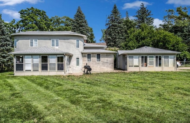 back of property with a sunroom, stucco siding, and a yard
