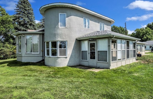 back of property with a yard, stucco siding, and a sunroom
