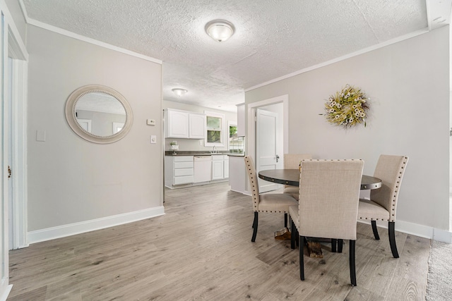 dining space featuring crown molding, sink, a textured ceiling, and light wood-type flooring