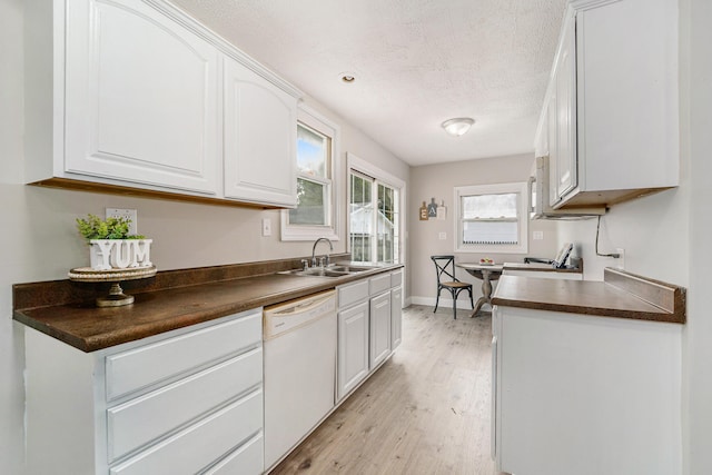 kitchen with white cabinetry, dishwasher, sink, light hardwood / wood-style flooring, and range